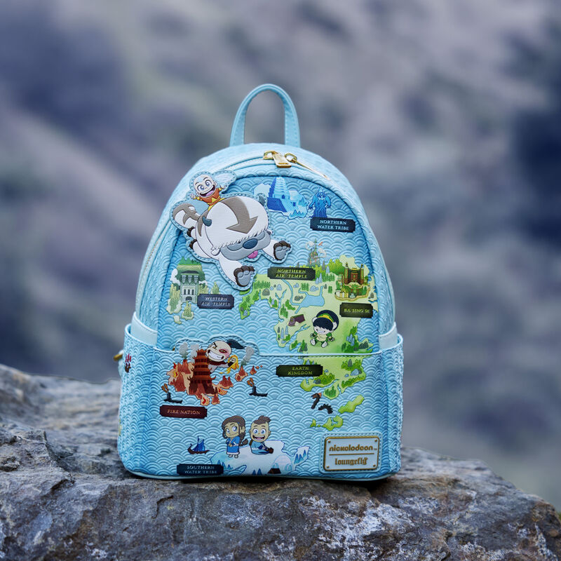 Blue Loungefly Avatar: The Last Airbender Map of the Four Nations Mini Backpack featuring a map with various locations from Avatar: The Last Airbender, like the Fire Nation, the Southern Water Tribe, and more, with various characters from the show on the map. The bag sits outside on a rock. 